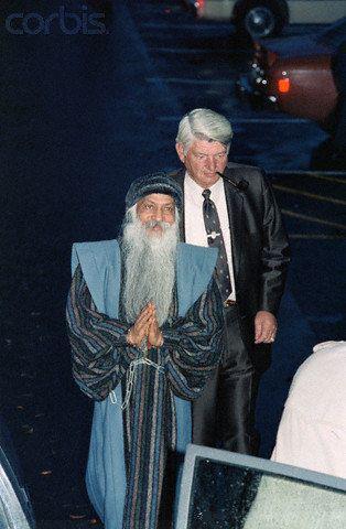 Osho arrested and in chains. He was later poisoned by talium while incarcerated without a warrant by the Reagan Administration. He was eventually released but the poison aged him 20 years in four and he died in January 1990.