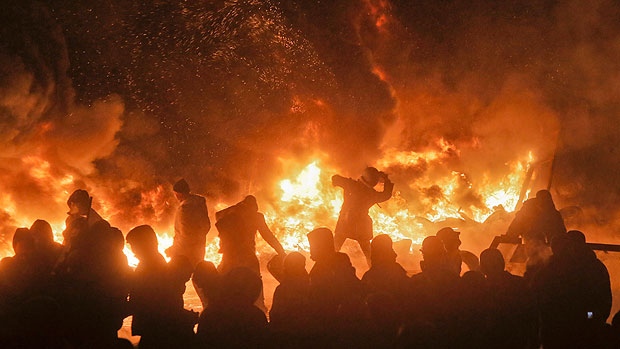 Protesters during the Maidan Revolution in Maidan Square, Kiev, Ukraine, throwing stones at the police on the other side of a constantly replenished barricade of flaming tires from November 2013 to February 2014. A coup of Ukrainian fascists violently broke with the peaceful resolution of the revolution on 22 February 2014, taking Ukraine on an infernal journey down an eight-year war in the Donbass to a new and expanded Russo-Ukrainian War in early 2022 that could escalate into a NATO-Russian War in the near future.