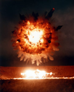 The explosion and blast fragments from a BGM-109 Tomahawk cruise missile destroy its target, a revetted aircraft, during a test conducted by the Joint Cruise Missiles Project. The missile was launched from a submerged submarine 400 miles off the coast of California. (Third view in a series of three)