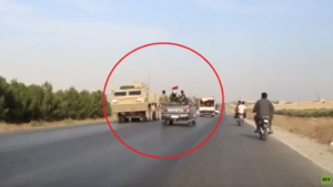 A US armored personnel carrier (left) in a convoy of US forces leaving Manbij, Syria, while a convoy of Syrian Arab Army forces (center) passes it, racing on its way to take up positions alongside the Kurds against a Turkish Army Invasion. Source: Ruptly.