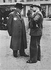 (Left phto) President Zelensky. (Center photo) Former Azov logo featuring a combination of a Wolfsangel and Black Sun, two symbols associated with the Wehrmacht and SS over a small Tryzub. (Right photo) Chaim Rumkowski, Jewish leader of the Lodz Ghetto. To the right is his Nazi handler, Hans Biebow. Source of Zelensky photo © Creative Commons. 
