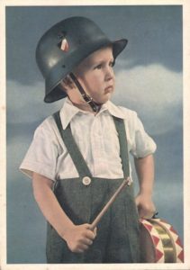 Third_Reich_Nazi_propaganda_postcard_of_boy_in_military_steel_helmet_(Wehrmacht_Stahlhelm)_holding_drum-Author-Uknown-©-unknown-cc4.0-International
